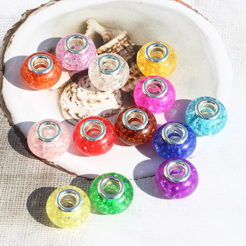 A collection of colorful resin spacer beads in various shades including pink, orange, yellow, and purple, arranged on a white