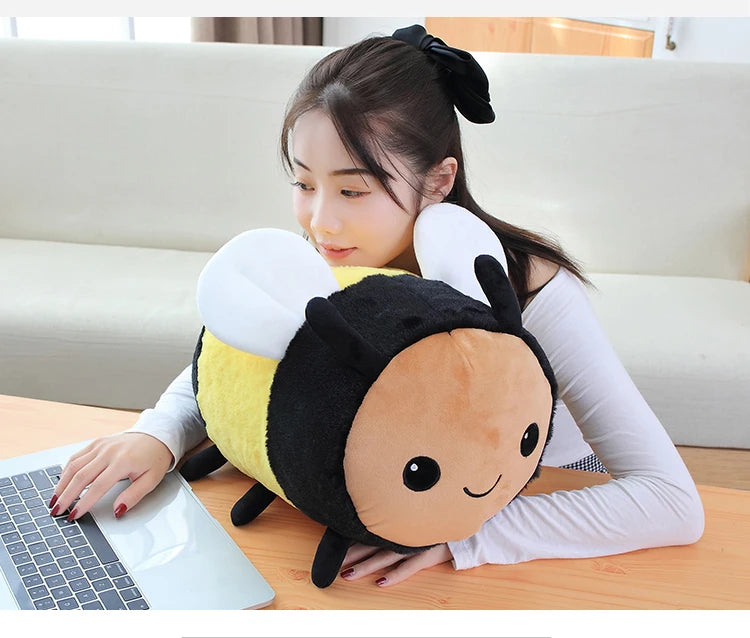 A young woman is holding a Kawaii Bee Ladybug plush toy while working on a laptop.