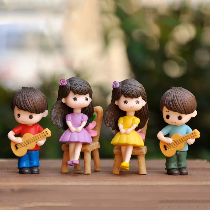 Three musical couple figurines with guitars and flowers displayed on a wooden surface.