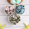 A collection of adorable sloth silicone beads in various shades of pink and blue are displayed on a white surface.