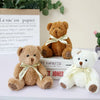 A set of three adorable teddy bear plush toys in various colors and sizes displayed next to a paper bag