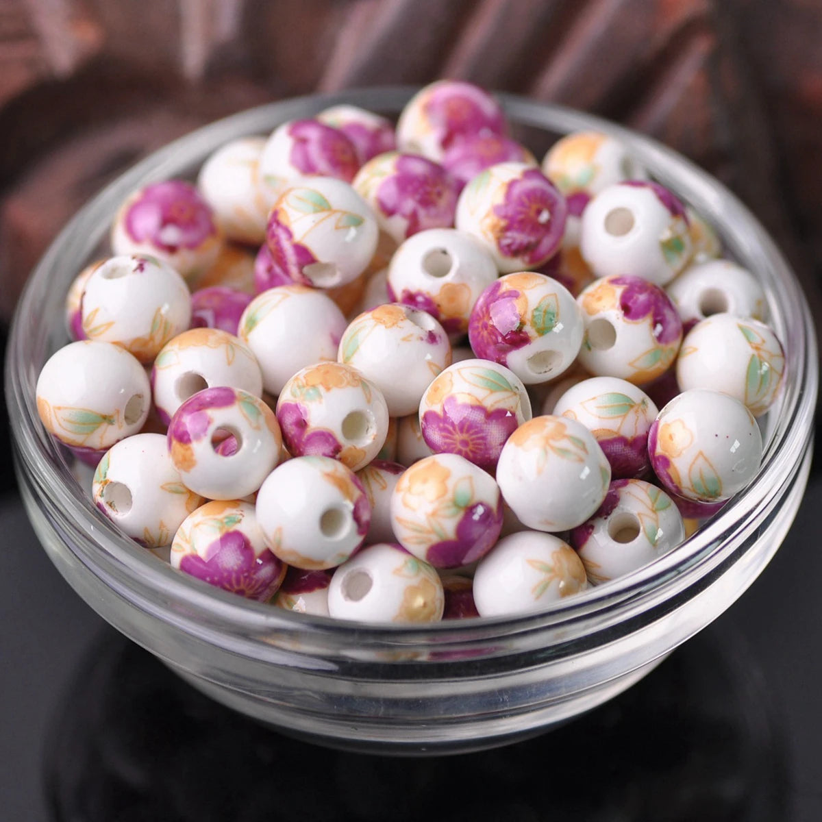 A bowl filled with small, round ceramic beads in shades of white and pink floral patterns for jewelry making