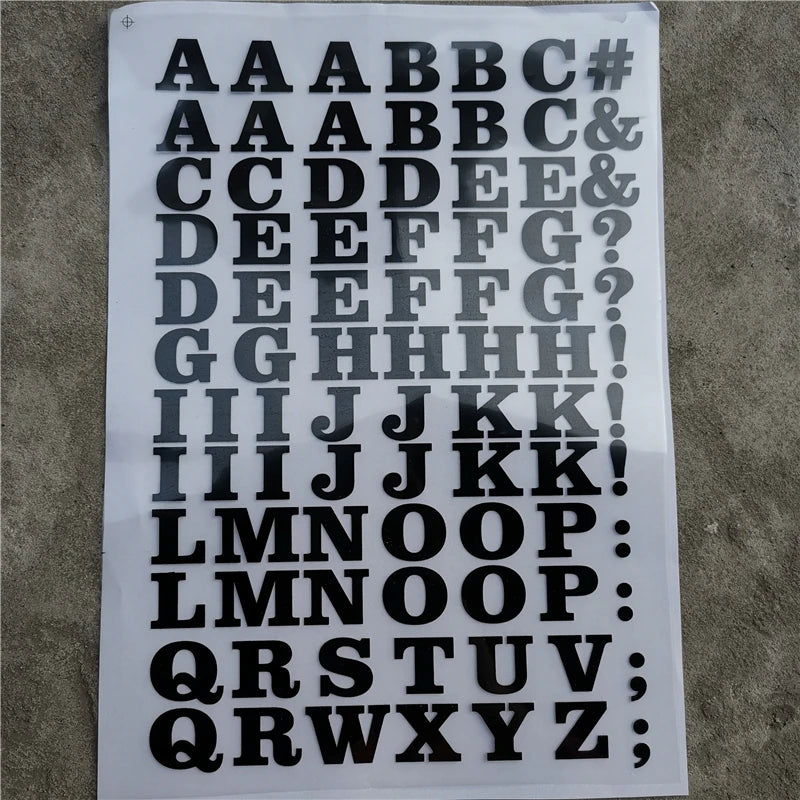 A sheet of DIY iron-on heat transfer patches showing various uppercase and lowercase letters and symbols.