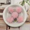 A white bowl filled with pink fluffy mink fur pom poms for crafts and accessories.