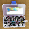 A clear plastic box contains various colorful plastic safety eyes for dolls and amigurumi.