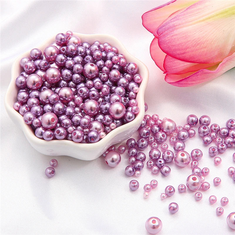 A pile of assorted purple and pink pearl beads scattered on a white surface.