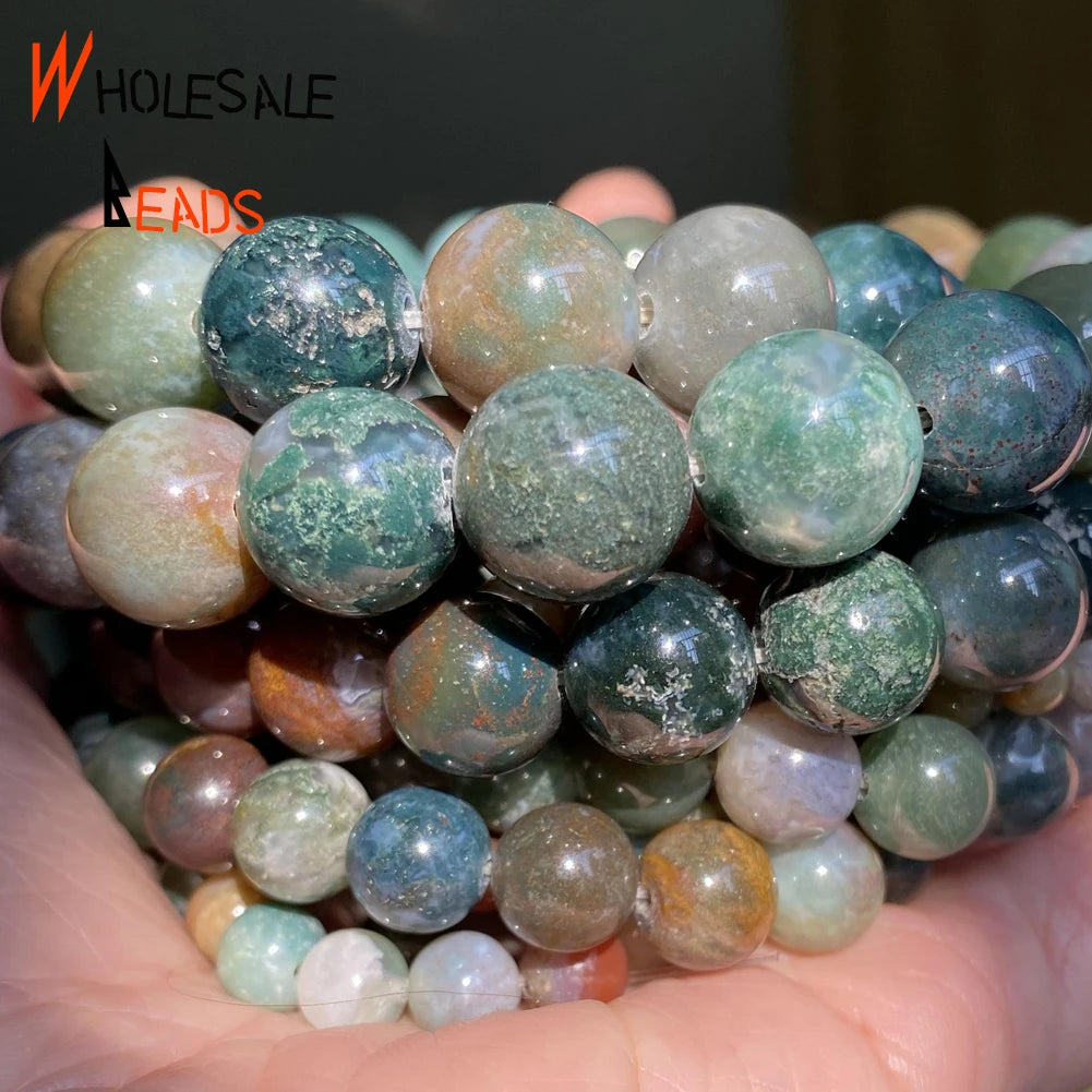 A close-up of a handful of natural gemstone beads including tiger eye, lava, and turquoise in various shades.