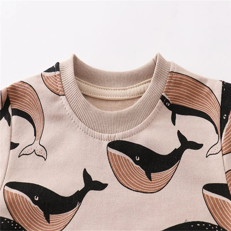 A beige long sleeve pullover sweatshirt featuring a repeating black whale print on the front.