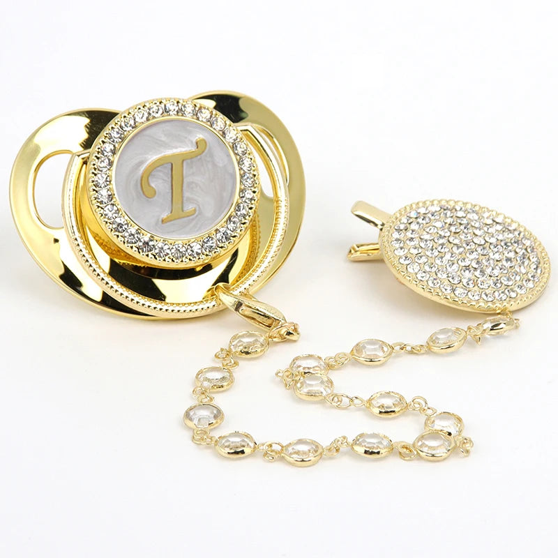 Gold rhinestone pacifier featuring a personalized initial design and clip.