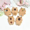 Five small brown teddy bear plush toys arranged on a white surface next to a laptop and a wire basket.