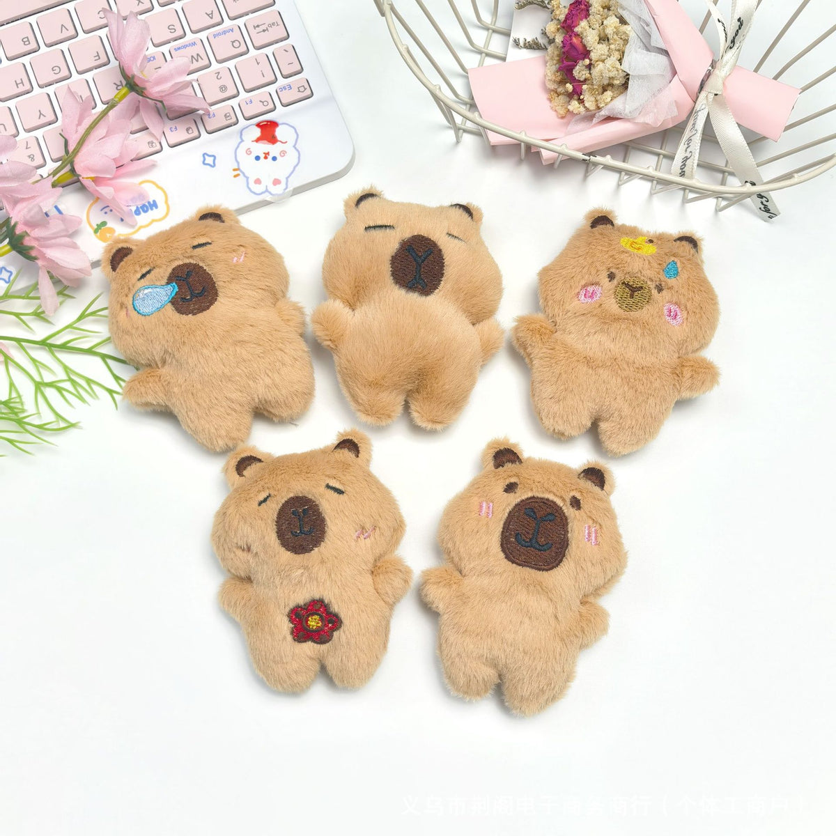 Five small brown teddy bear plush toys arranged on a white surface next to a laptop and a wire basket.