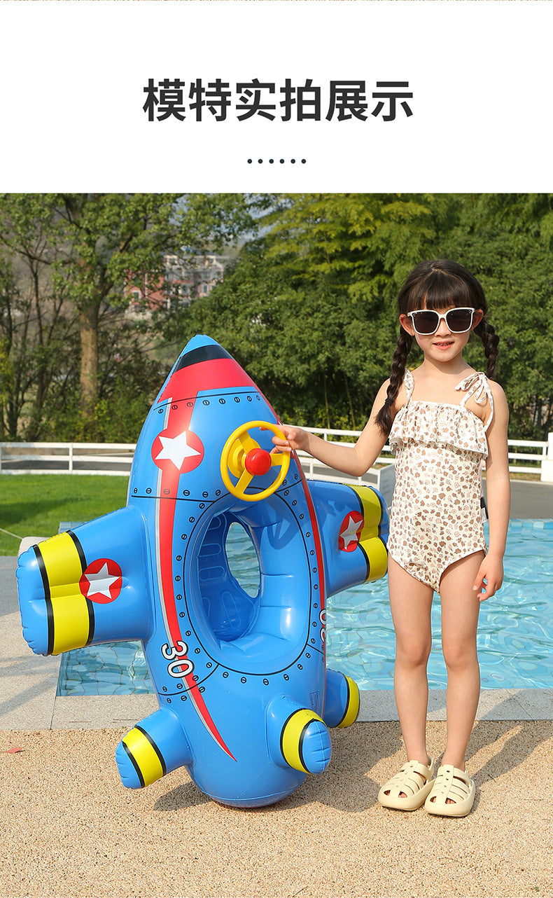 A young girl is standing next to a blue inflatable aircraft swim ring for kids outdoors.