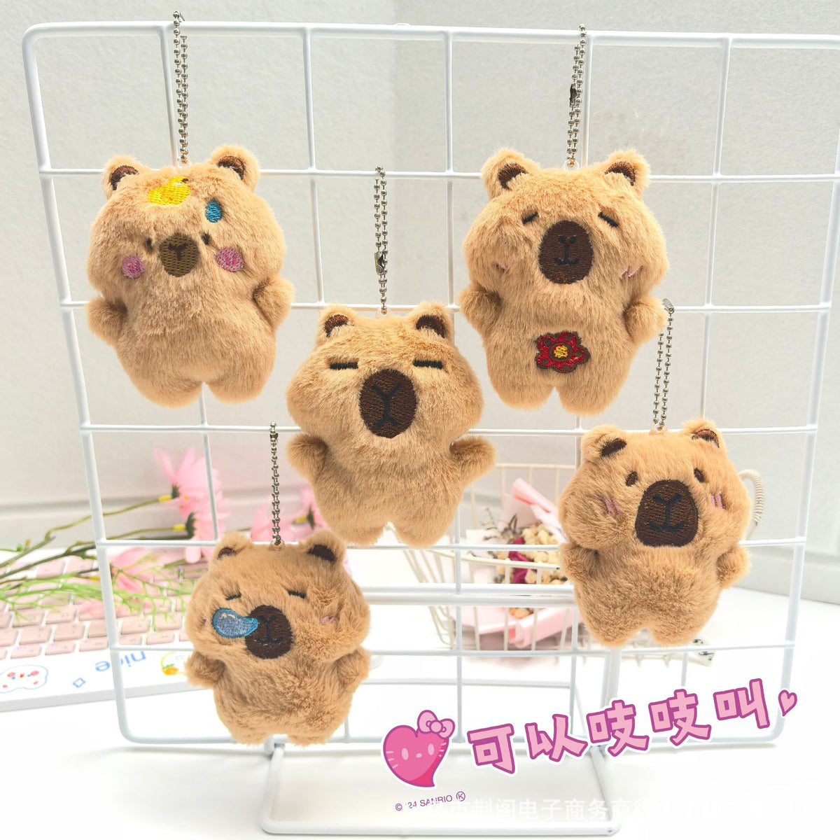A display of several fluffy brown capybara plush toys hanging in a white wire grid.