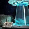 A clear dome display featuring an alien spaceship model and building blocks set with lights against a dark background.