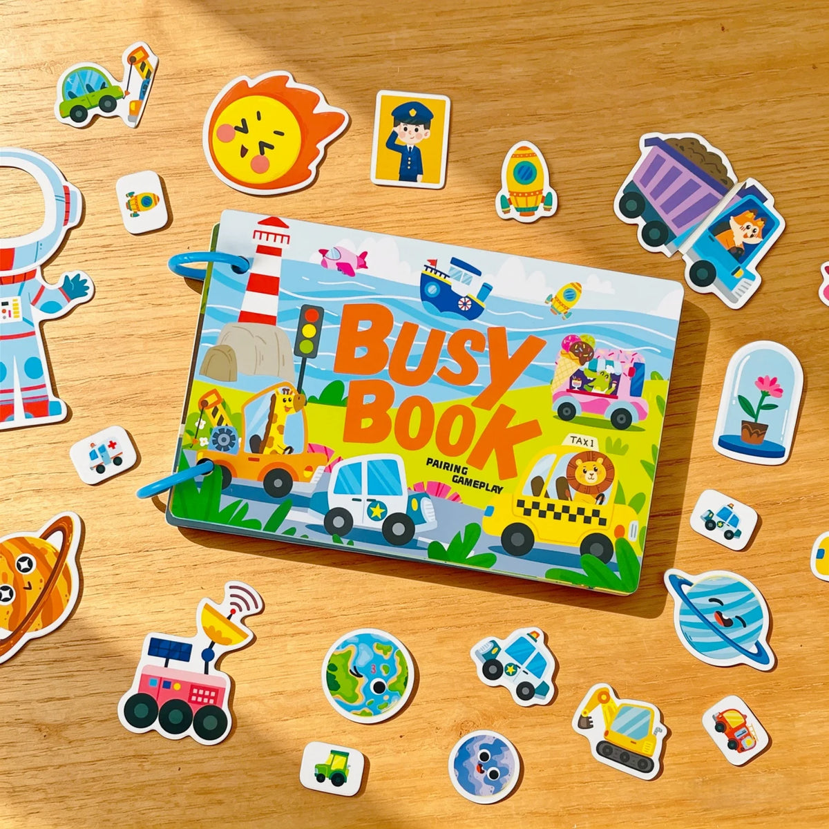 A colorful busy book for toddlers featuring various activity cards and toys on a wooden surface.