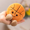 An orange plush sports ball companion with stitched lines and small feet is held in a hand.