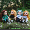 Four orange and red-haired BJD princess dolls with various outfits sitting on a mossy rock in a lush green garden.