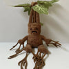 A brown mandrake plush toy with large leaves, standing on a white surface.