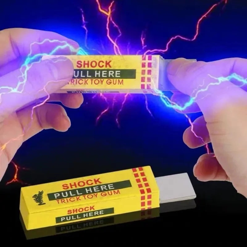 Hands hold a yellow box of shock pull here trick toy gum with visible electric lightning effects.