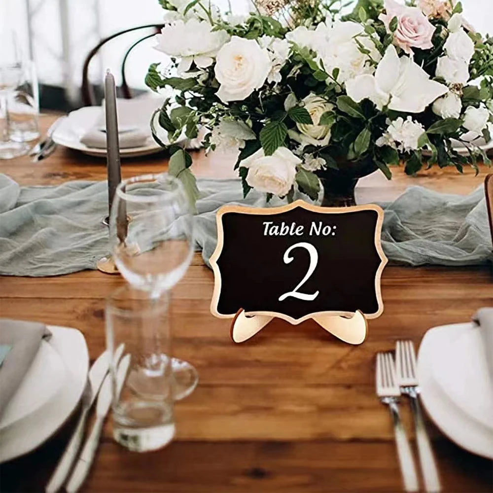 A wooden chalkboard sign with the number 2 on an easel placed on a rustic wooden table setting.