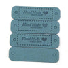 A set of four rectangular, teal-colored leather-style tags with the text Handmade with love engraved on them.