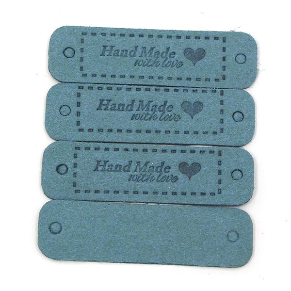 A set of four rectangular, teal-colored leather-style tags with the text Handmade with love engraved on them.