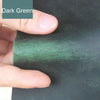 A hand is holding a piece of dark green leather for DIY crafting or leatherwork.