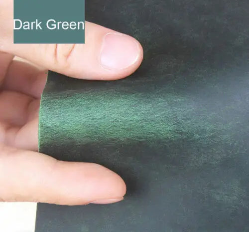 A hand is holding a piece of dark green leather for DIY crafting or leatherwork.
