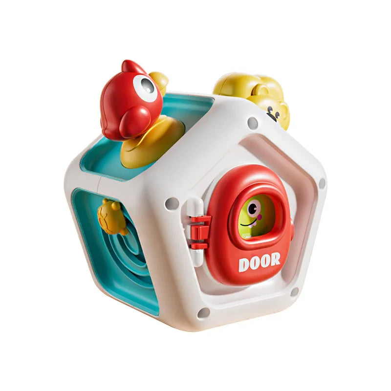 A white cube toy with a red door and yellow animal figures, designed for sensory play.