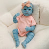 A lifelike reborn baby doll with blue skin and pink clothing is resting on a white, fluffy surface.