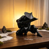 A black 3D printed samurai warrior figurine statue with a sword displayed on a wooden surface.