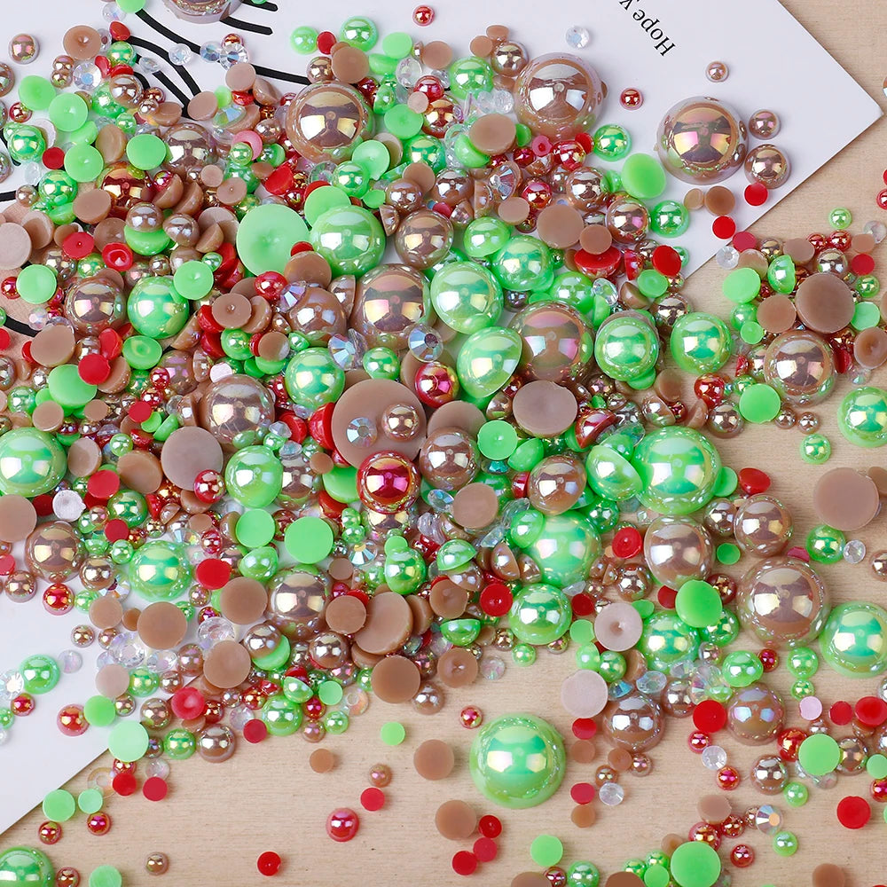 A scatter of mixed resin rhinestone pearls in various shades including green, pink, and gold on a white background.