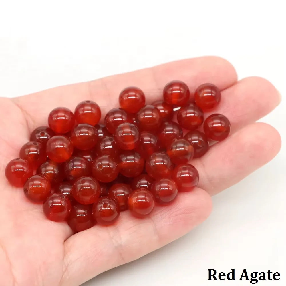 A handful of smooth, round, reddish-orange agate beads for jewelry making.