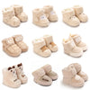 A collection of beige baby winter cartoon boots for infants, shown in various styles and colors.