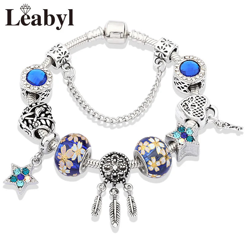Silver crystal charm bracelet featuring blue stones and green leaf floral accents.