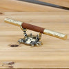 Brass crab figurine with a wooden handle resting on a light wood surface.