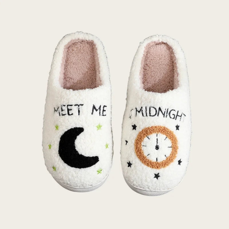A pair of white plush indoor slippers featuring a crescent moon and a clock design on the sole.