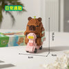 A small, brown capybara-shaped building block figure on a pink cart, displayed next to its packaging.