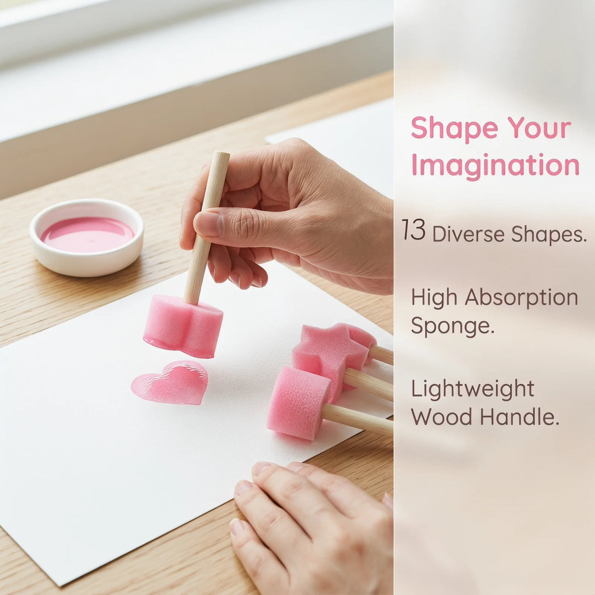 A hand is using a pink sponge stamp on white paper, demonstrating the use of a lightweight wooden handle for an arts and craf