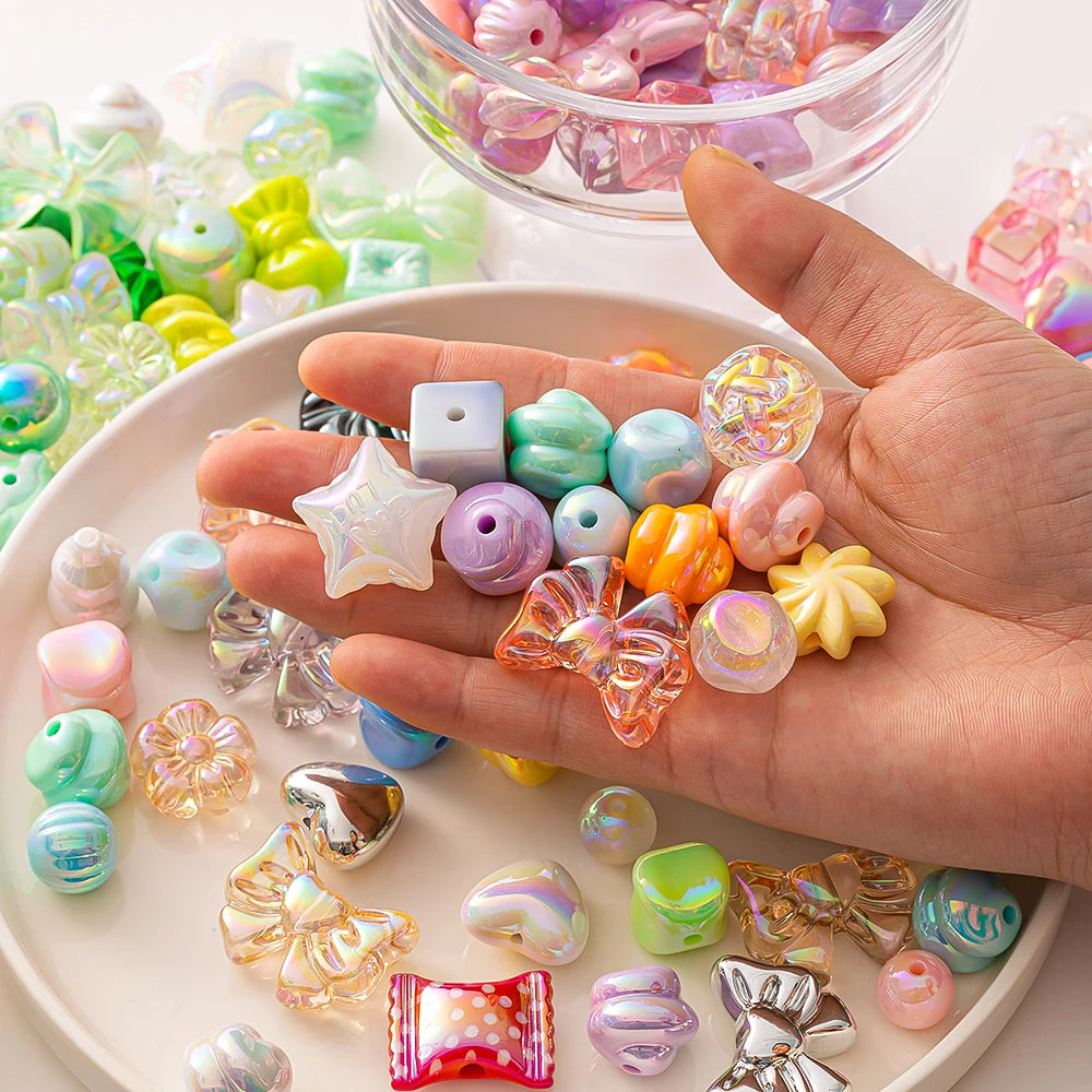 A hand holds various colorful acrylic bow and flower beads for DIY jewelry making.