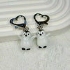 A set of two ceramic penguin heart keychains with silver clasps displayed on a white surface.
