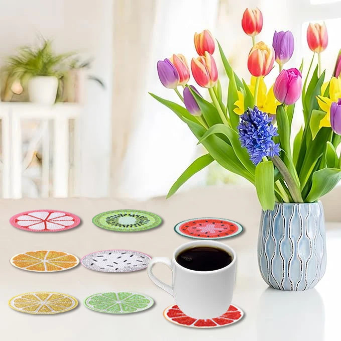 Une collection de sous-verres de peinture diamant à motifs de fruits colorés, exposés sur une surface blanche.