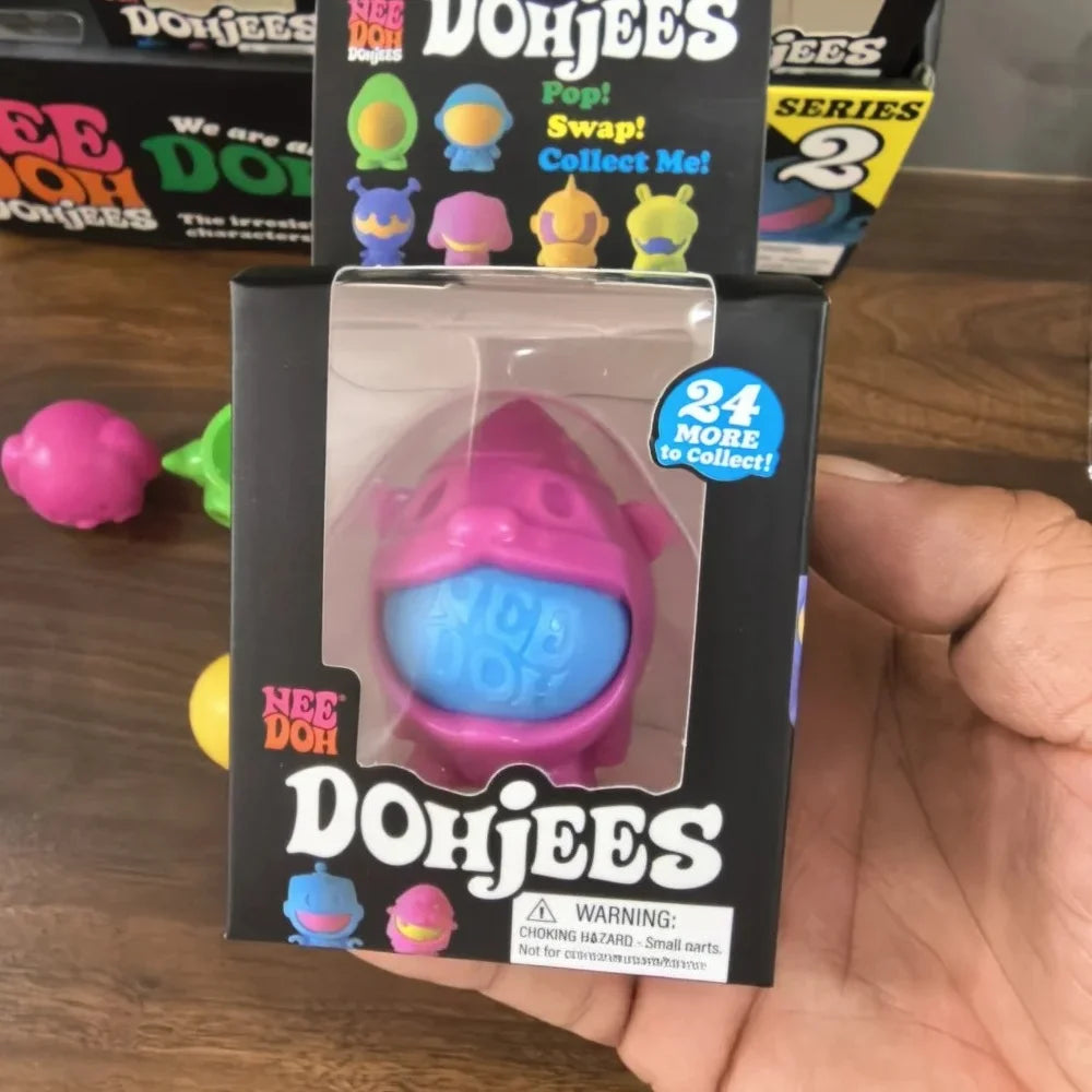 A packaged Dohjees squishy toy in pink and blue colors is held in a hand.