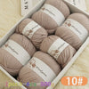 A box filled with ten balls of light beige merino wool yarn for knitting