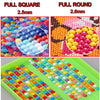 A collection of colorful, small, round beads and stones arranged in rows on a green tray.