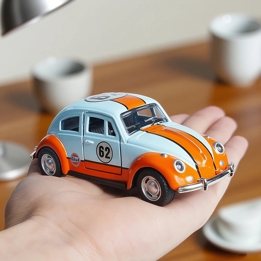A hand holds a 1:36 scale die-cast retro Beetle car painted light blue and orange, featuring opening doors.
