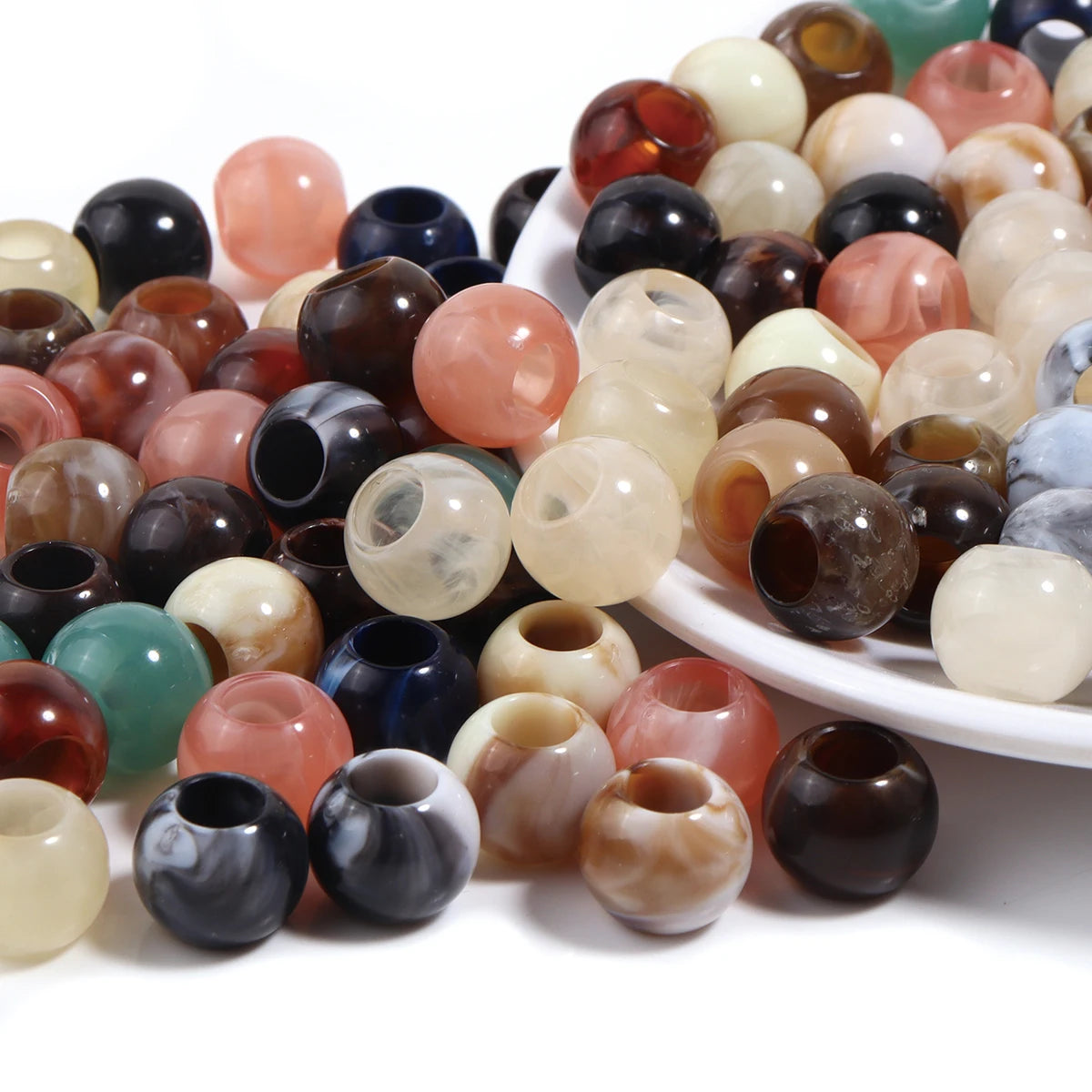 A collection of 50 imitation jade acrylic cloud beads in various translucent and opaque colors arranged on a white dish.