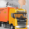 A yellow diecast container truck model is shown with a hand pressing a trigger to activate sound and light features.