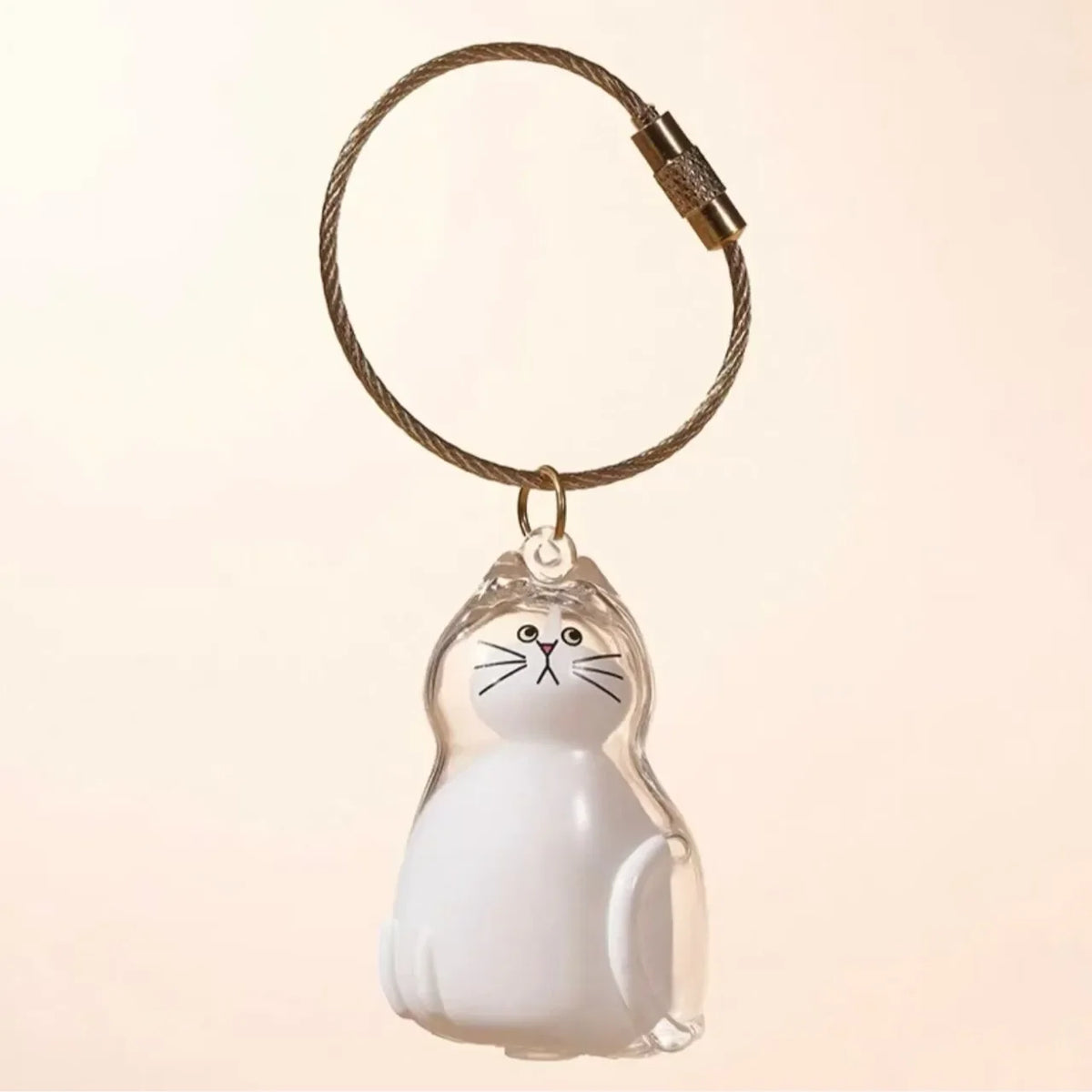 A clear, dog-shaped pet hair keepsake keychain with a white cat figure attached to a braided cord.