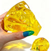 A hand holds a yellow, cheese-shaped squishy fidget toy with multiple holes against a white background.